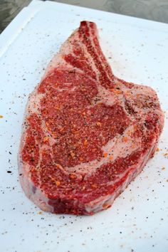 a piece of raw meat sitting on top of a cutting board covered in seasoning