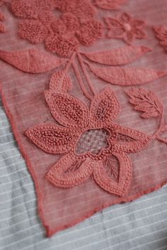 an embroidered piece of cloth with flowers and leaves on the edge is laying on a bed