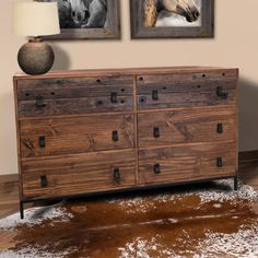 a dresser with two pictures on the wall above it and a rug in front of it