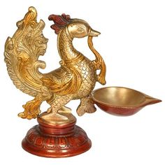 a golden rooster statue sitting on top of a wooden stand next to a metal bowl