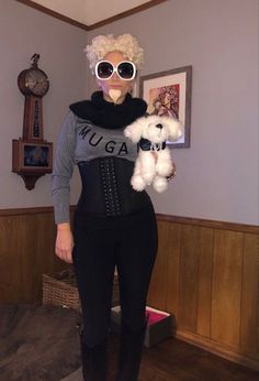 a woman with white hair and sunglasses holding a stuffed animal in her arms while wearing a black corset