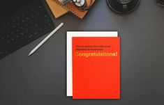 an orange congratulations card sitting on top of a desk next to a keyboard and mouse