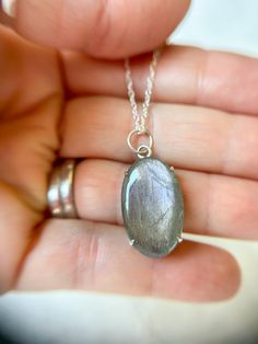 This gorgeous flashy oval Labradorite cabachon is delicately prong set in sterling silver and features an open back to light the light come in and sparkle! The necklace hangs from a graduated sized jump rings hanging on a 20” Sterling Silver Chain. Each piece of GreenHillJewelry is handmade in our El Dorado Hills, CA studio. We proudly use Recycled Sterling Silver. Please allow for natural variations that may occur.This order will ship in 1-2 business days via first class USPS unless Priority Sh Iridescent Oval Sterling Silver Jewelry, Oval Pendant Jewelry With Natural Inclusions In Silver, Oval Silver Labradorite Jewelry, Oval Jewelry With Natural Inclusions For Jewelry Making, Iridescent Oval Gemstone Necklaces, Silver Labradorite Oval Jewelry, Iridescent Oval Gemstone Necklace, Elegant Oval Labradorite Pendant Jewelry, Silver Oval Labradorite Necklace