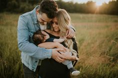 a man and woman holding a baby in a field