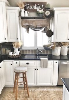 a kitchen with white cabinets, black counter tops and a wooden stool in front of the sink