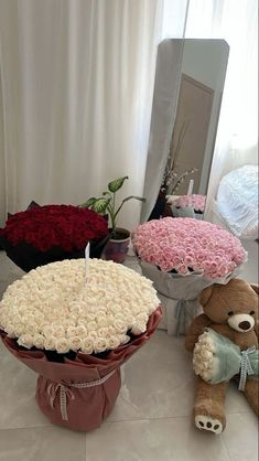 two teddy bears sitting in front of a large cake with roses on it and another stuffed bear next to the cake