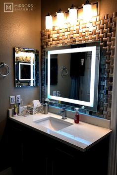 a bathroom with a sink, mirror and lights on the side of the counter top