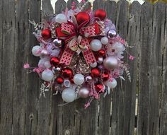 a wreath with red, white and silver ornaments hanging on a fence