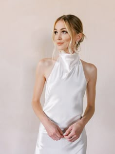 a woman in a white dress posing for the camera with her hands on her hips