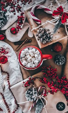 a table topped with red and white christmas decorations next to wrapping paper wrapped in twine