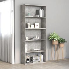 a book shelf with books and plants on it in a living room next to a window