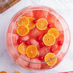 orange slices and cherries in a bowl of ice water with cranberries on the side