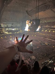 a person holding their hand up in front of an audience at a concert with the lights on