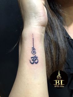 a woman's wrist tattoo with an omen symbol on it