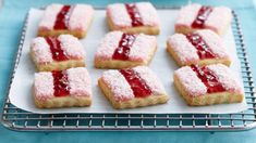 strawberry shortbreads with powdered sugar and jelly filling on a baking sheet, ready to be baked