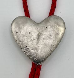 The ultimate symbol of love -- the heart. This elegant heart-shaped pewter Bolo Tie is a perfect gift for your lover, for a wedding, an anniversary or a birthday. The 2 in by 2 in pewter heart was casted using a mold made from silicone. Customers can select the length of the cord from kid size 32 inches to adult tall size 42 inches. Also buyers can customize the color of the cord from red (shown), black or brown. The cord itself is genuine braided leather. Weather it is for Valentines Day or sim Silver Heart Necklace For Valentine's Day, Silver Spiritual Heart Necklace For Valentine's Day, Spiritual Silver Heart Necklace For Valentine's Day, Bolo Tie Necklace, Mens Leather Necklace, Gift For Valentines Day, Tie Necklace, Love Marriage, Tie Gifts