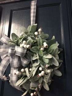 a wreath is hanging on the door with white berries and greenery attached to it