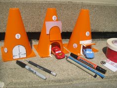 there are three traffic cones, markers, pens and pencils on the ground next to each other