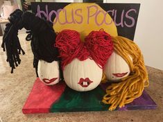 two pumpkins with hair on top of them sitting on a counter next to a sign