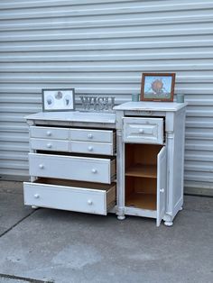 an old dresser with drawers and pictures on it's top shelf next to a garage door