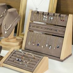 an assortment of jewelry on display in front of a wooden frame with mirror behind it