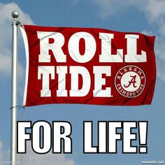 a red and white flag with the word roll tide on it in front of a blue sky