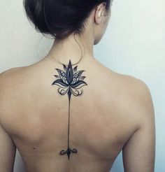 the back of a woman's neck with a flower tattoo on it