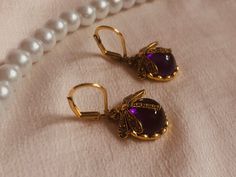 Immerse yourself in the nostalgic elegance of gold-plated vintage gold earrings, decorated with a mysterious purple natural stone and a delicate dragonfly. The delicate dragonfly, captured in its golden shine, symbolizes lightness and transformation. These earrings pay tribute to bygone eras where beauty and grace were found in the details. Wear these unique earrings and be seduced by their timeless beauty. A touch of vintage glamor for every occasion that perfectly highlights your personality a Nickel-free Gold Dragonfly Jewelry, Elegant Hypoallergenic Dragonfly Earrings, Elegant Gold Dragonfly Jewelry, Elegant Dragonfly Jewelry For Wedding, Elegant Dragonfly Jewelry For Jewelry Making, Gold Nickel-free Dragonfly Earrings, Nickel-free Gold Dragonfly Earrings, Elegant Purple Earrings For Her, Elegant Purple Earrings As A Gift For Her