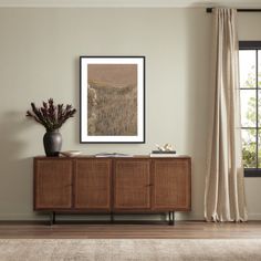 a living room with a large window and a wooden cabinet in front of the wall