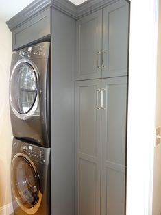 a washer and dryer are in the corner of this laundry room with cabinets