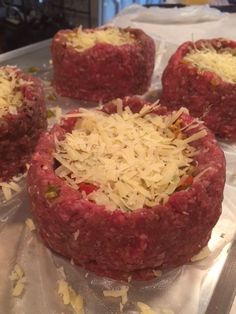 four raw meatloaf patties with shredded cheese on top