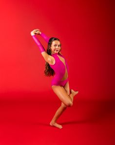 a young woman in a pink leotard poses for a photo on a red background