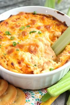 a casserole dish with celery and crackers next to it on a table