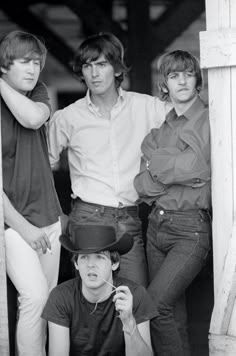 the rolling stones pose for a portrait in front of an open doorway, wearing hats and jeans