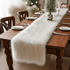 a table with a white fur runner on it and place settings in front of the table