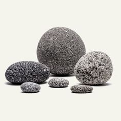 several rocks are arranged in the shape of an egg, and one is black with white speckles