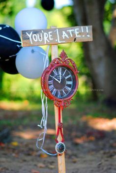 a clock with a sign that says you're late hanging from a wooden pole