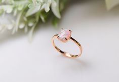 a pink opal ring sitting on top of a white table next to some flowers