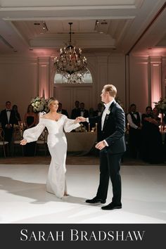 a bride and groom dance together at their wedding reception in the ballroom with chandeliers