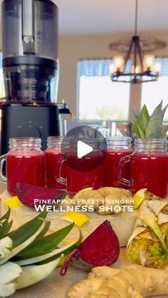 there are many fruits and vegetables on the table with juices in mason jars next to them