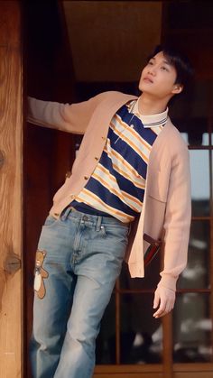 a young man leaning on the side of a wooden structure with his hands in his pockets