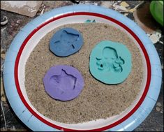 three cookie molds on a plate with sand in the shape of an elephant and dog