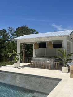 an outdoor kitchen and dining area next to a pool