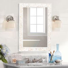 a bathroom with a sink, mirror and flowers on the counter top in front of it