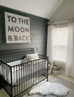 a baby's room with a black metal crib and white rug on the floor