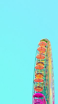 a ferris wheel with colorful umbrellas on it's sides against a blue sky