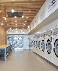 an empty laundry room with several washers and dryers in the center, all lined up