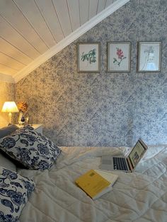 a laptop computer sitting on top of a bed in a room with blue and white wallpaper