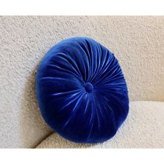 a blue round pillow sitting on the back of a white couch next to a wall