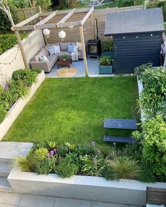 a small backyard with grass and flowers in the center, an outdoor seating area on the other side